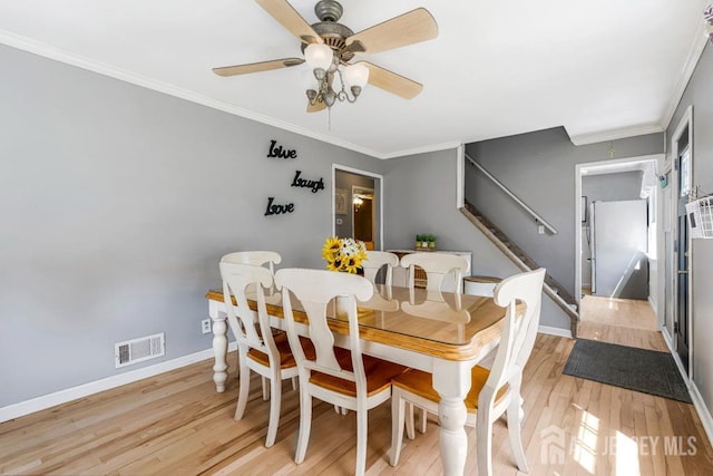 dining area with ceiling fan, visible vents, light wood-type flooring, baseboards, and stairs