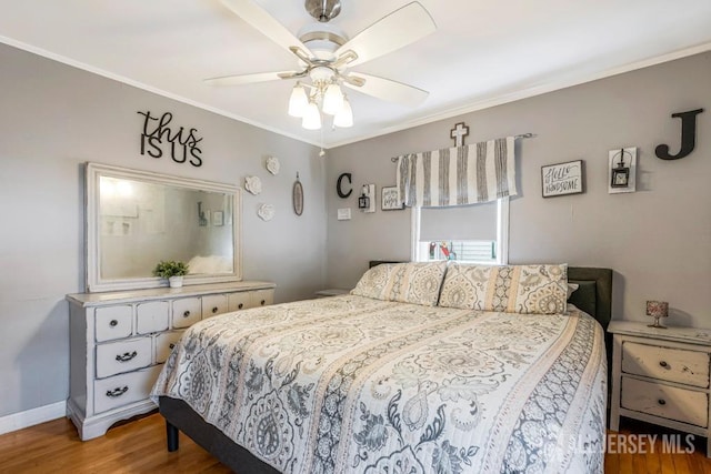 bedroom with a ceiling fan, baseboards, ornamental molding, and wood finished floors