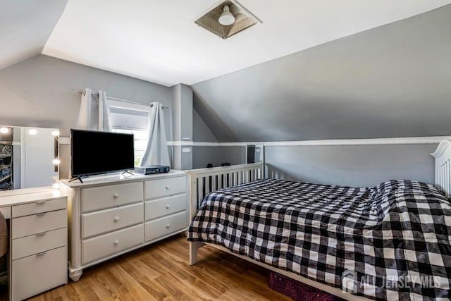 bedroom with light wood-style flooring and lofted ceiling