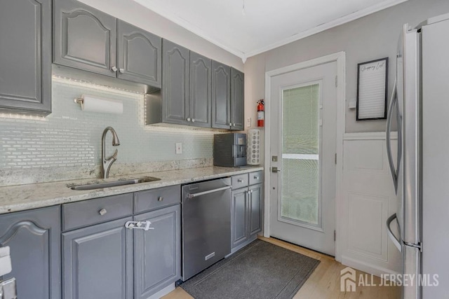 kitchen featuring crown molding, a sink, appliances with stainless steel finishes, backsplash, and gray cabinetry