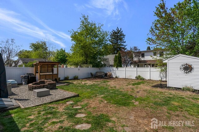 view of yard featuring a fire pit, an outdoor structure, a fenced backyard, a shed, and a patio area