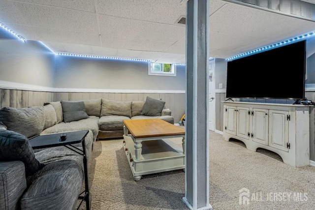 living area featuring light colored carpet, a paneled ceiling, wainscoting, and visible vents