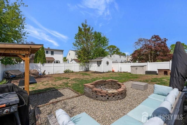 view of yard featuring an outdoor structure, a fenced backyard, an outdoor living space with a fire pit, and a shed