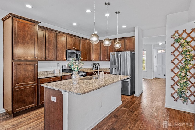 22 Larkspur Ln, Monroe, NJ 08831 - kitchen featuring appliances with stainless steel finishes, dark wood-style floors, light stone counters, a center island with sink, and decorative light fixtures