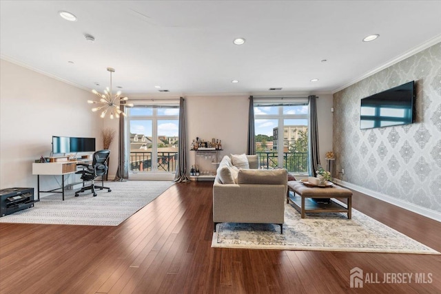 living area with wallpapered walls, plenty of natural light, wood-type flooring, ornamental molding, and a chandelier