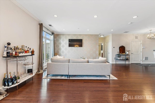 living room with ornamental molding, an accent wall, wallpapered walls, baseboards, and wood finished floors
