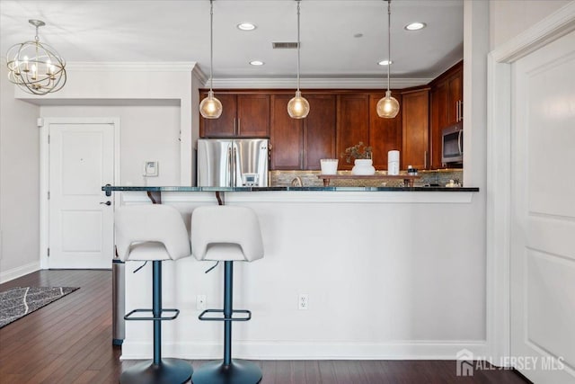 kitchen featuring appliances with stainless steel finishes, backsplash, a kitchen breakfast bar, dark wood-style flooring, and recessed lighting