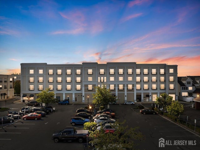 property at dusk with uncovered parking and view of commercial area