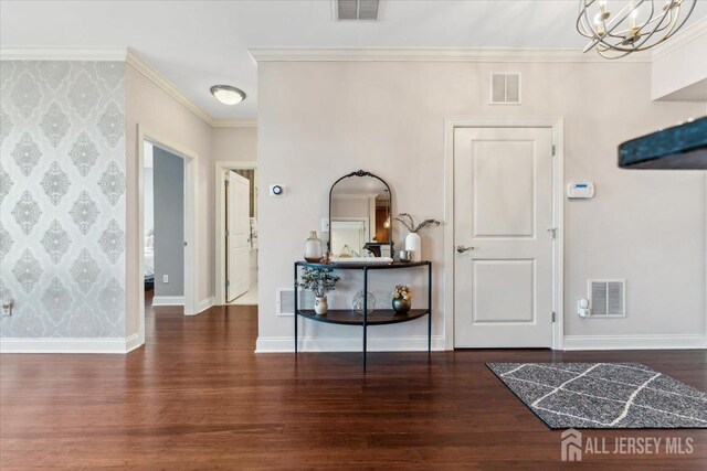 entryway featuring wood finished floors, a chandelier, crown molding, and baseboards