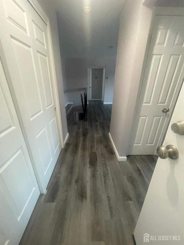 hallway with dark wood finished floors and baseboards