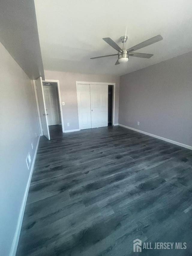 unfurnished bedroom featuring visible vents, a ceiling fan, a closet, baseboards, and dark wood-style flooring