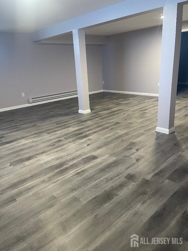 finished basement featuring dark wood-style floors, baseboard heating, and baseboards