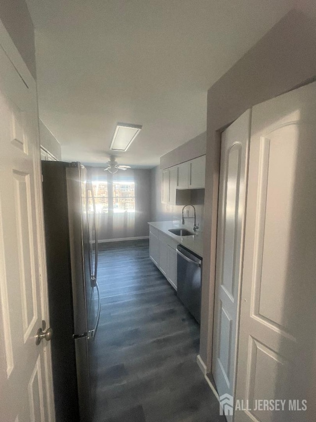 hall featuring dark wood-type flooring, baseboards, and a sink