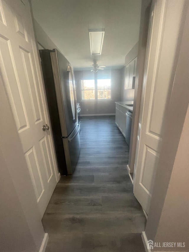 hallway featuring baseboards and dark wood-style flooring