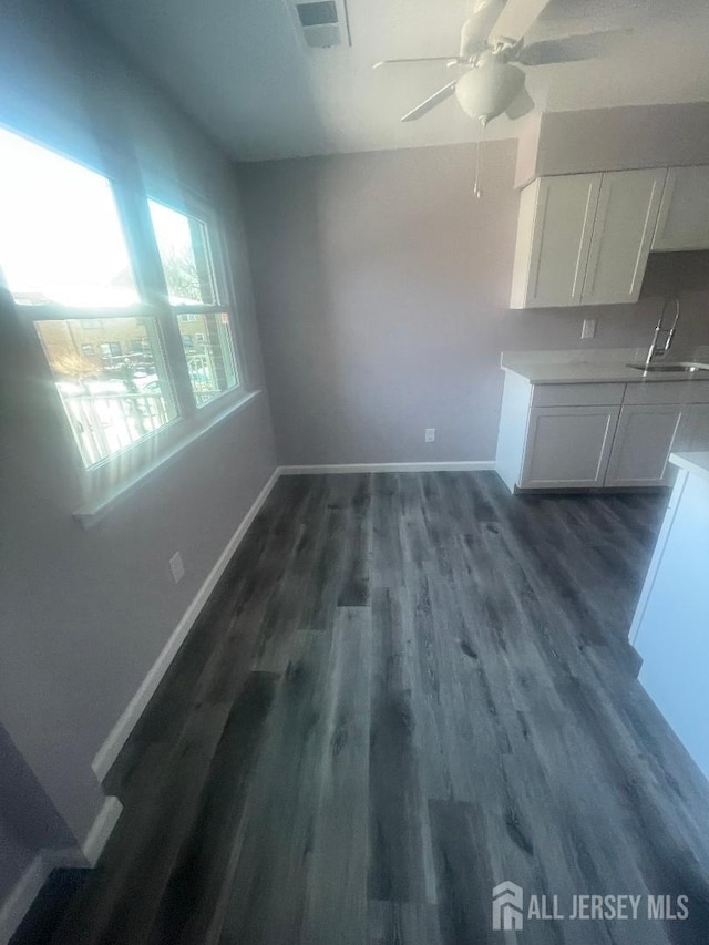 unfurnished dining area featuring sink, ceiling fan, and dark hardwood / wood-style flooring