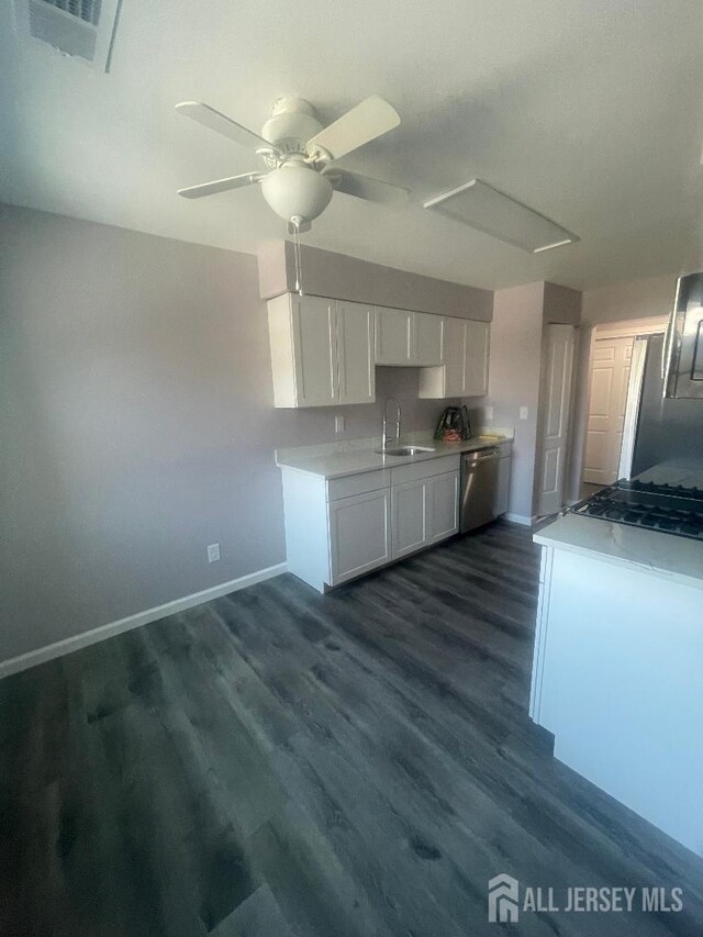 kitchen featuring appliances with stainless steel finishes, white cabinetry, sink, ceiling fan, and dark hardwood / wood-style floors