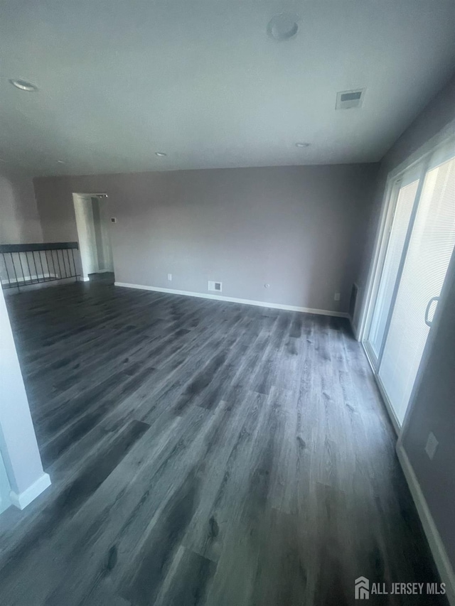 spare room featuring visible vents, baseboards, and dark wood finished floors