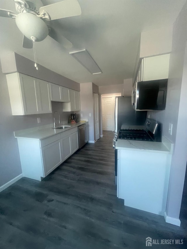 kitchen featuring dark wood-style floors, a sink, light countertops, white cabinets, and appliances with stainless steel finishes