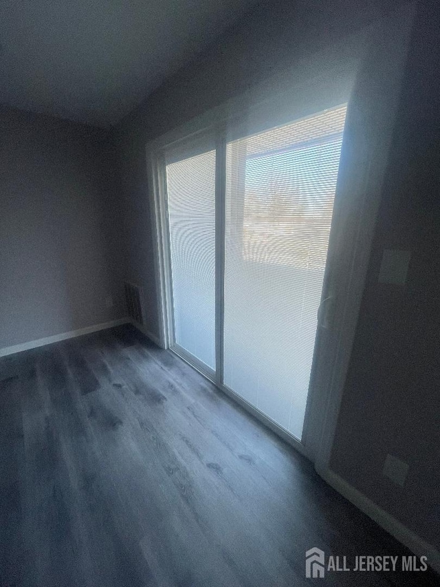 unfurnished room with visible vents, baseboards, and wood finished floors