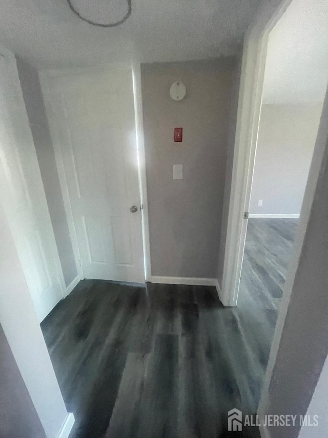 hallway featuring baseboards and wood finished floors