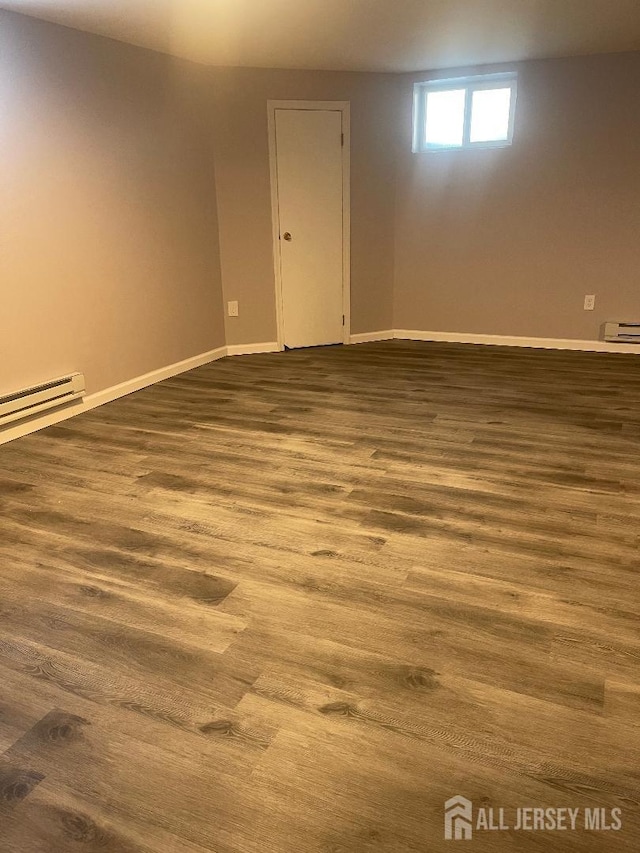 basement with a baseboard radiator, baseboards, baseboard heating, and dark wood finished floors