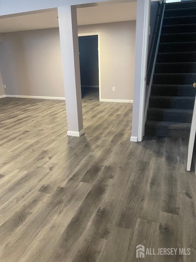 finished below grade area with dark wood-style floors, stairs, and baseboards