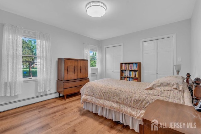 74 Ravine Dr, Matawan, NJ 07747 - bedroom featuring two closets, baseboard heating, and light wood-style floors