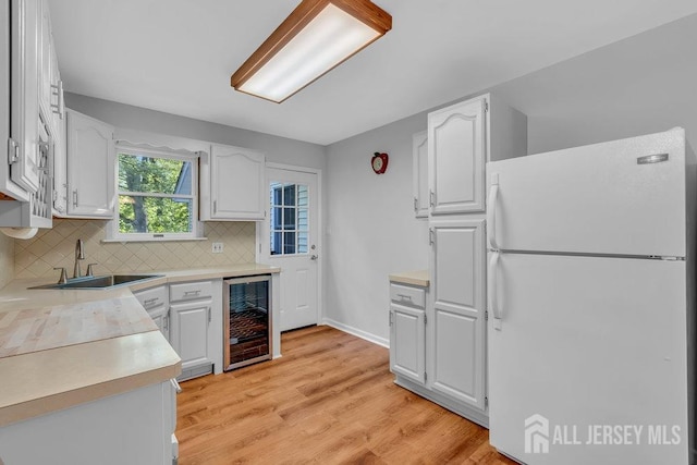 74 Ravine Dr, Matawan, NJ 07747 - kitchen with freestanding refrigerator, beverage cooler, white cabinetry, and decorative backsplash