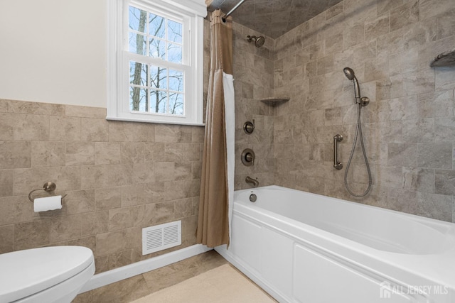 bathroom featuring shower / bath combo with shower curtain, toilet, visible vents, and tile walls