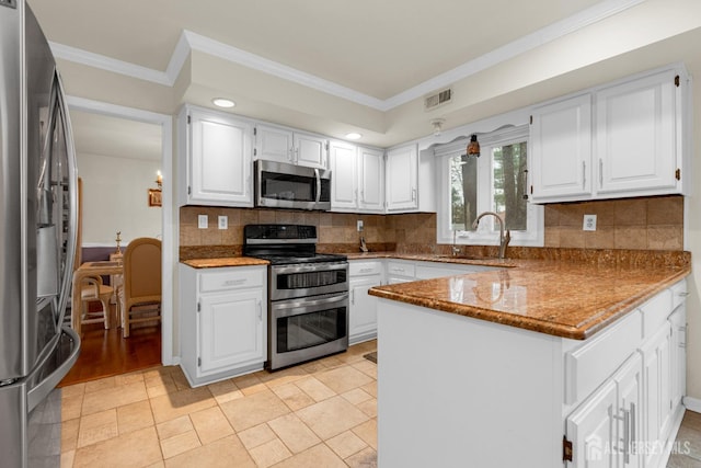 kitchen featuring a sink, a peninsula, stainless steel appliances, visible vents, and crown molding