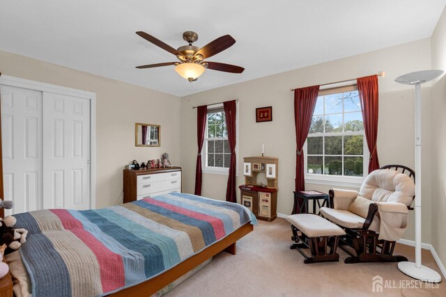 carpeted bedroom with multiple windows, a closet, and ceiling fan