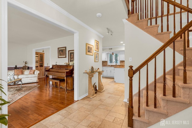 foyer entrance featuring crown molding, stairway, and baseboards