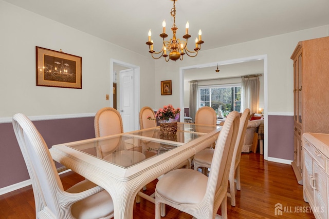 dining room featuring baseboards, an inviting chandelier, and dark wood-style floors