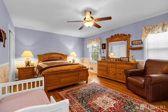 bedroom featuring wainscoting, ceiling fan, visible vents, and wood finished floors
