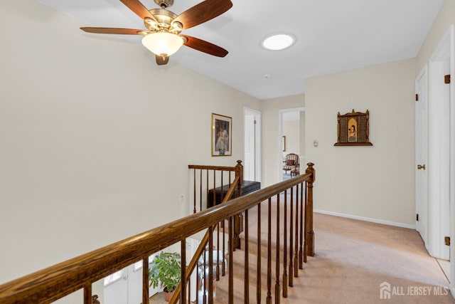 hallway featuring light colored carpet, an upstairs landing, and baseboards