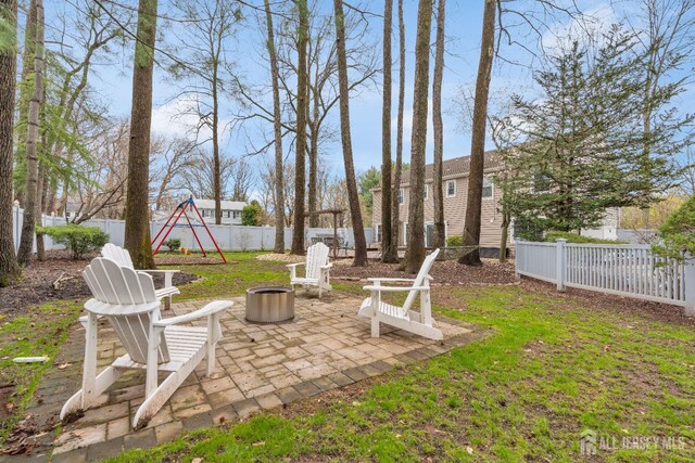 view of yard featuring an outdoor fire pit, a playground, a patio area, and a fenced backyard