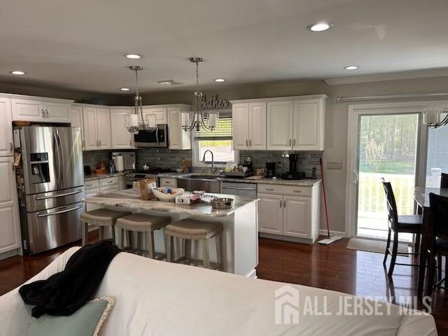 kitchen with appliances with stainless steel finishes, a sink, plenty of natural light, a chandelier, and ornamental molding