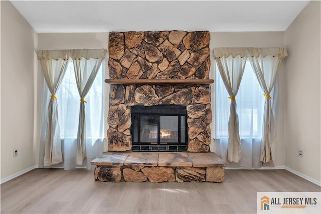 details with a stone fireplace, wood finished floors, and baseboards