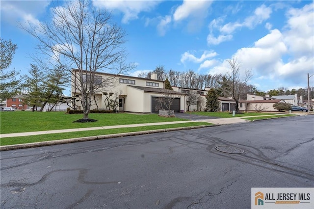 view of front of property featuring a garage, driveway, a residential view, and a front lawn