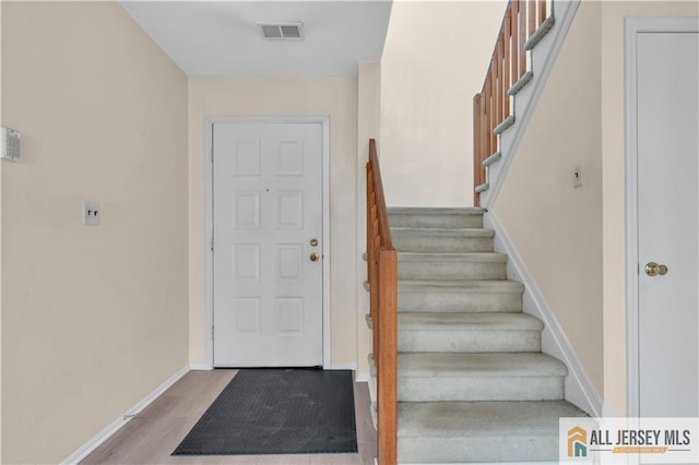 staircase with visible vents, baseboards, and wood finished floors