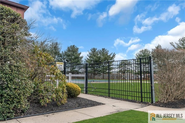 view of gate featuring a lawn and fence