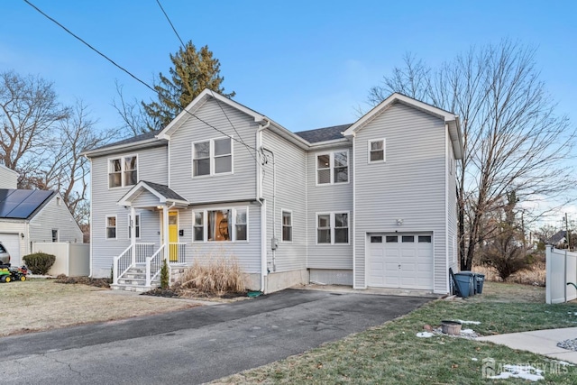 view of front facade with aphalt driveway, fence, and an attached garage