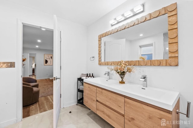 bathroom with double vanity, baseboards, a sink, and recessed lighting