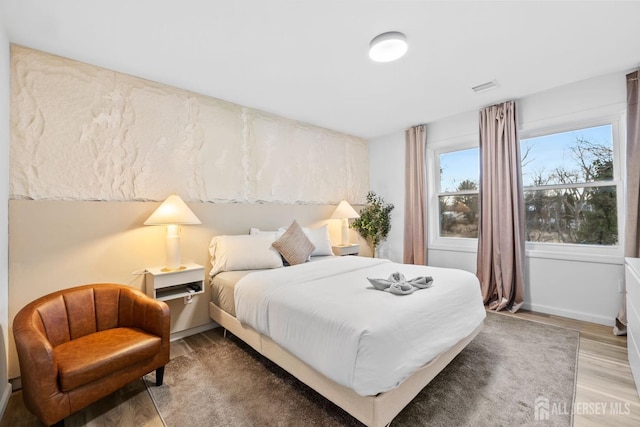 bedroom with baseboards, visible vents, and light wood finished floors