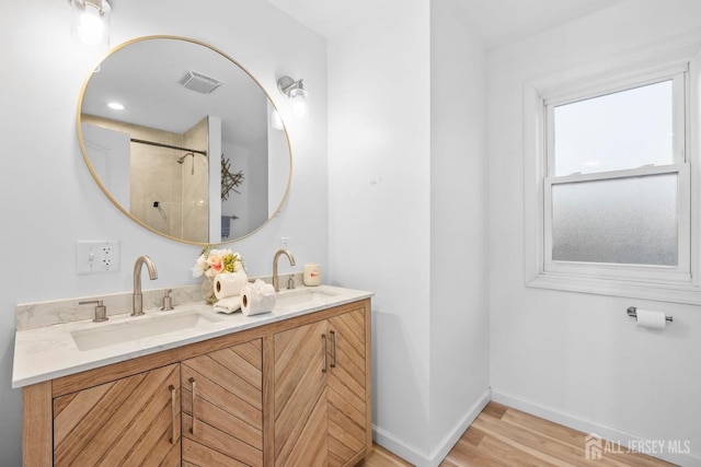 full bath featuring wood finished floors, a sink, visible vents, and baseboards