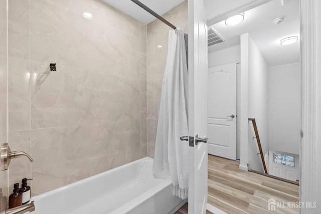 bathroom featuring visible vents, shower / bath combination with curtain, and wood finished floors