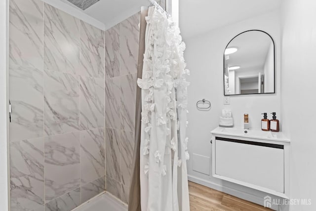 bathroom featuring a tile shower, vanity, and wood finished floors