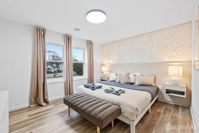 bedroom with visible vents, light wood-style flooring, and baseboards