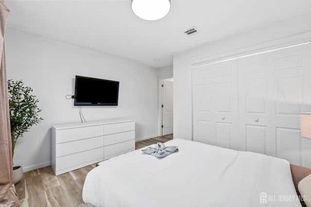 bedroom with light wood-style floors, a closet, visible vents, and baseboards