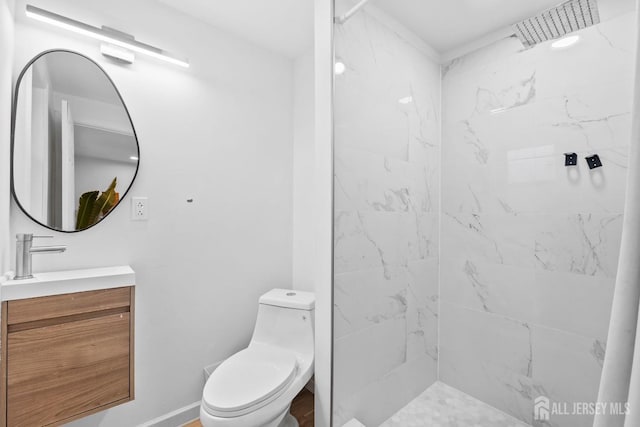 bathroom with vanity, a marble finish shower, toilet, and baseboards